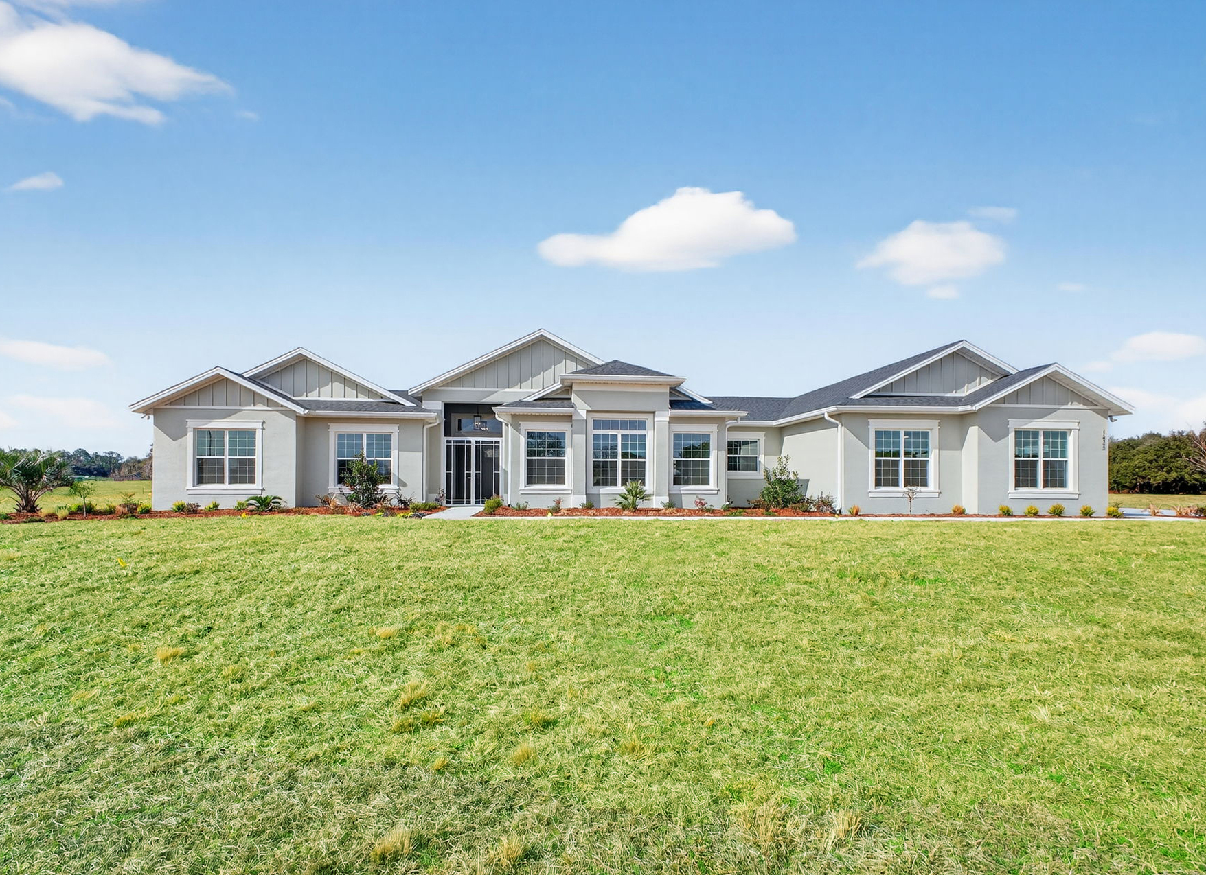 Front exterior photo of the completed Newcastle model home featuring stone accents and a paved driveway at Oxford Landings
